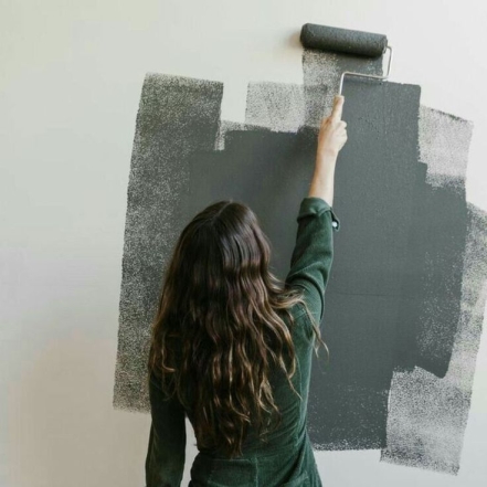 Женщина окрашивает стену, фото