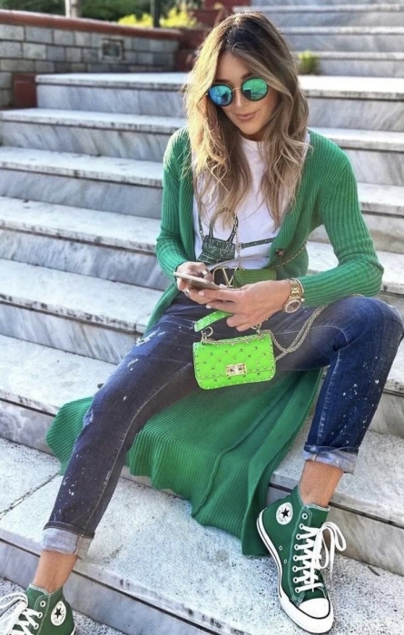 Жінка у джинсах, зелених кедах і кофтині