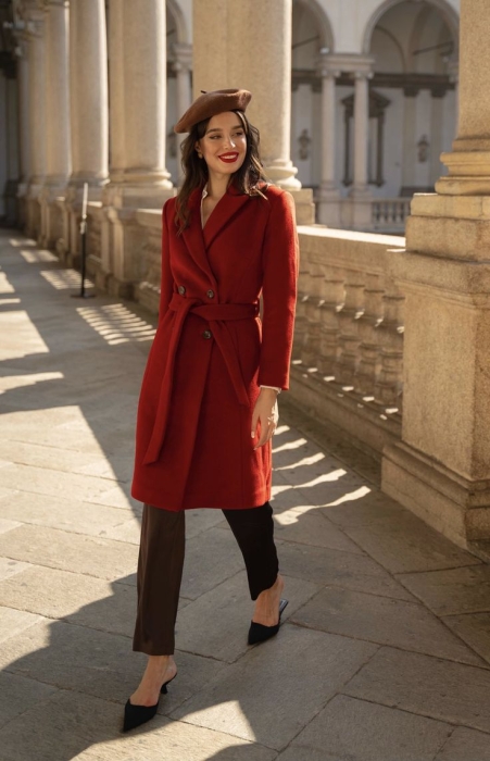 Жінка у червоному пальто, коричневих брюках і капелюсі, фото