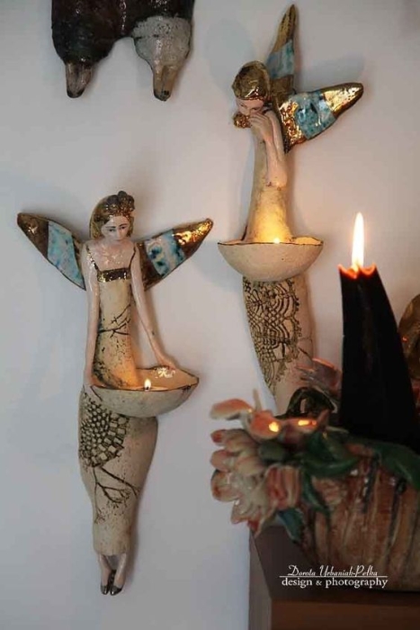 Статуэтки ангелов висят на стене и держат свечи, фото