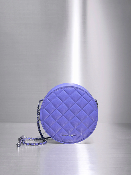 На фото круглая фиолетовая сумка