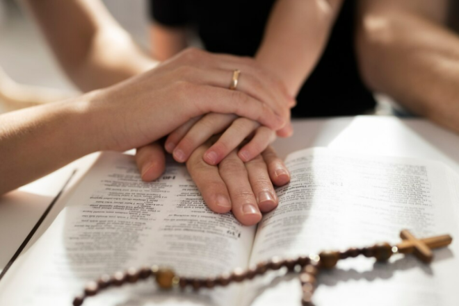 Семья молится, положив руки на Библию, фото