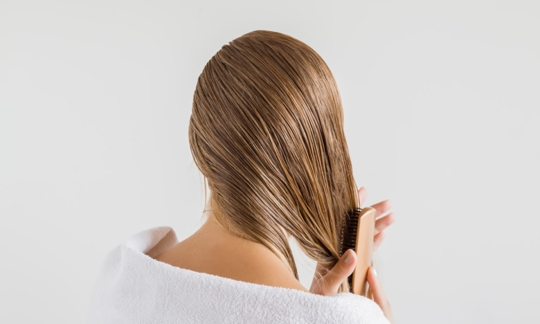 На фото жінка розчесує мокре волосся