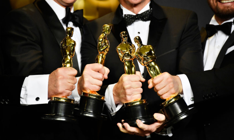 Чоловіки тримають в руках статуетки Оскар, фото