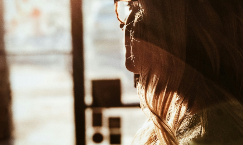 Женщина в очках смотрит в окно фото