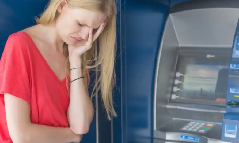 На фото засмучена жєінка біля банкомата