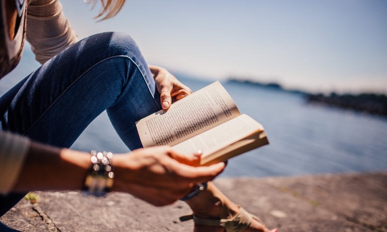 Женщина читает на берегу моря, фото