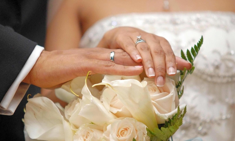 Изображение свадебного букета и рук с кольцами.