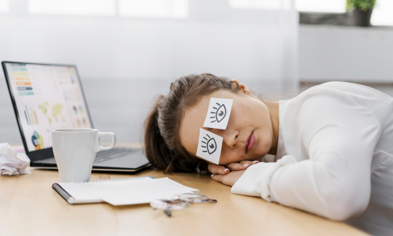 Изображение женщины, которая спит за рабочим столом