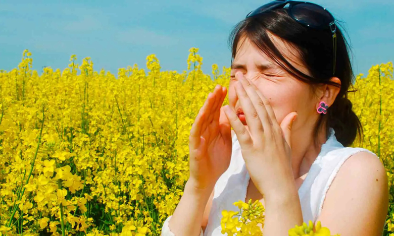 На фото женщина в поле чихает