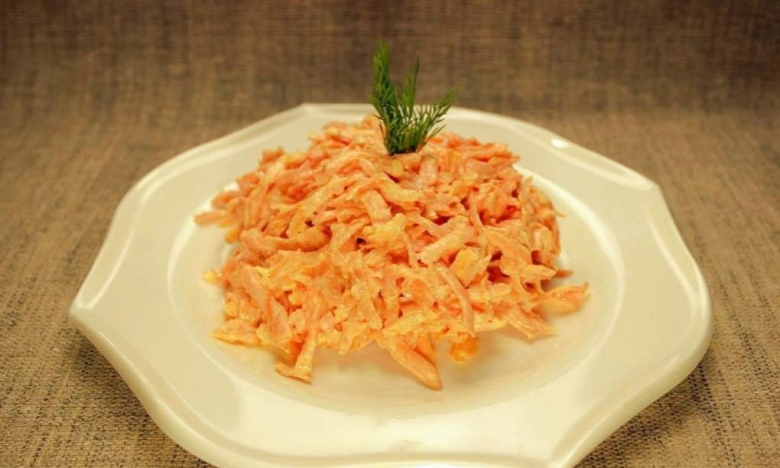 Салат из сырой моркови и плавленого сыра на тарелке.