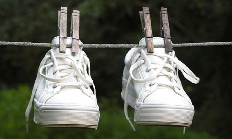 Белые кроссовки подвешены на веревке