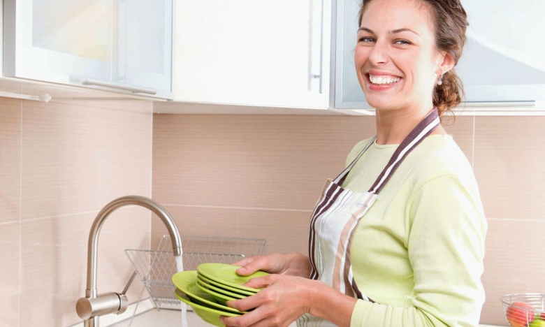 На фото жінка миє посуд