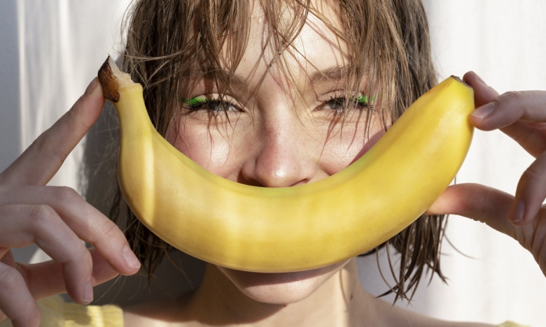 свежий банан на фоне лица