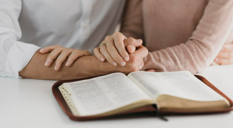 Пара молиться, тримаючись за руки, фото